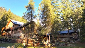 Ein großes, hölzernes Chalet mit Natursteinfassade, mehreren Terrassen und einer gepflegten Umgebung.
