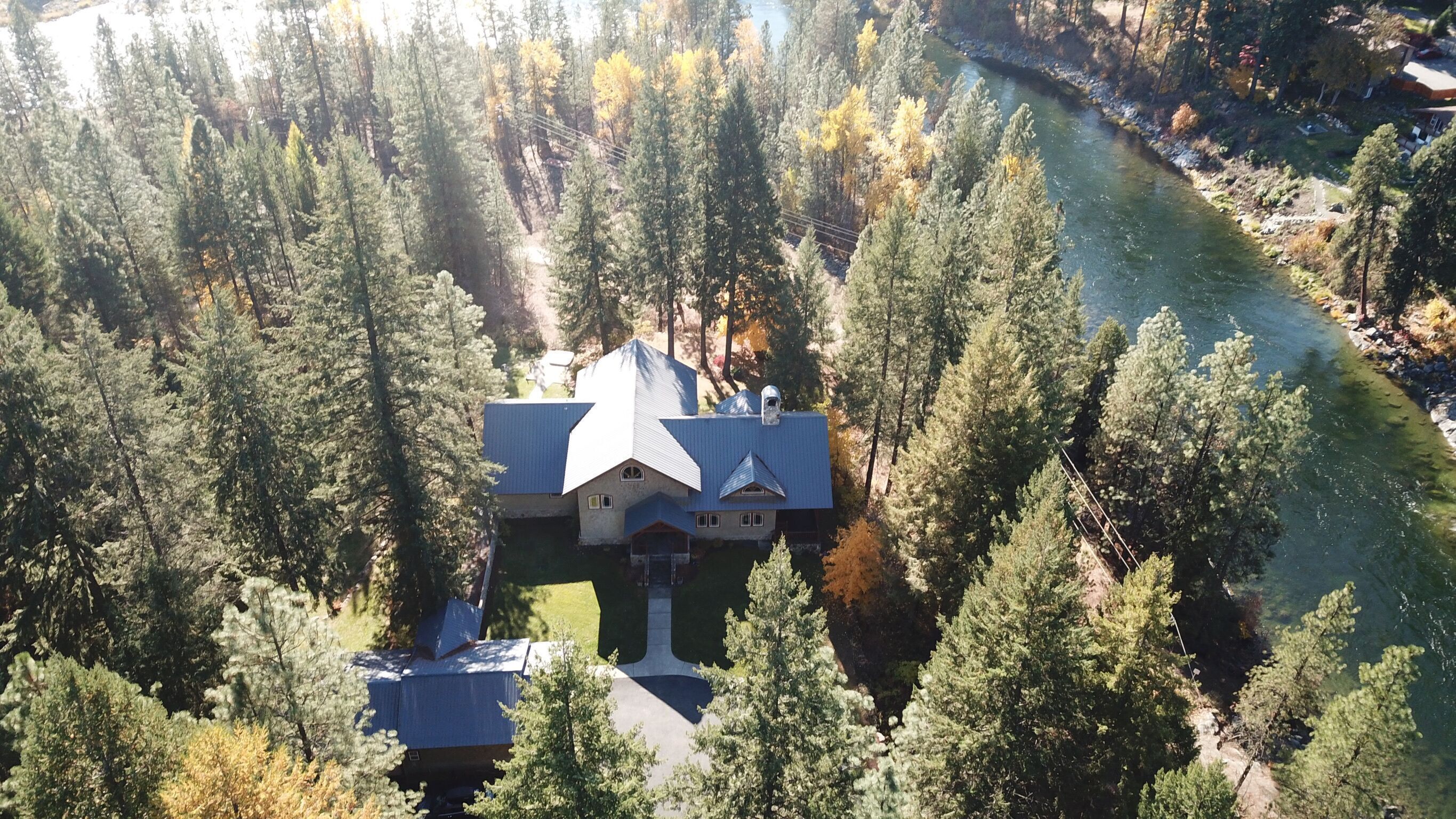 Une grande maison entourée d’une forêt dense, avec une rivière à proximité.