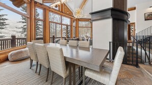 Une salle à manger spacieuse avec un haut plafond, de grandes fenêtres et une cheminée.