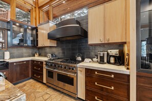 Une cuisine moderne équipée d’une cuisinière Viking, d’une machine à café et d’une grande fenêtre donnant sur un paysage enneigé.
