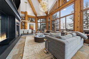 A spacious living area with a fireplace, large windows, and a cozy seating arrangement. - Spacious Horseshoe Hideaway Escape (Vail)