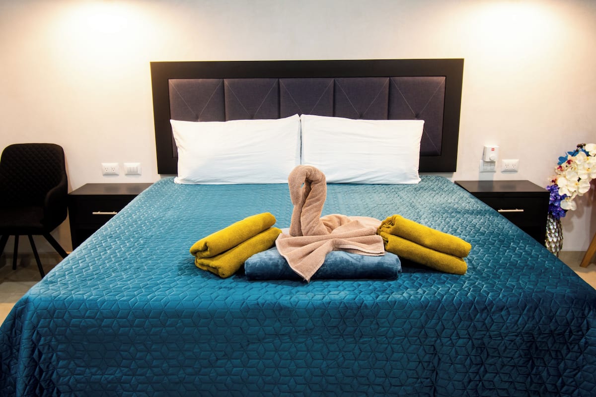 A hotel room with a bed, two nightstands, a chair, and a vase with flowers.