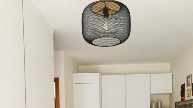 Une cuisine compacte avec des meubles blancs, une table à manger avec des chaises bleues et un luminaire suspendu.
