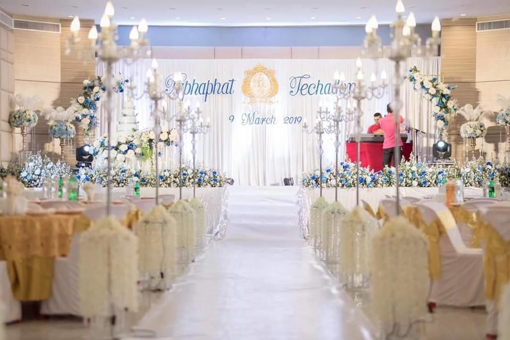 A wedding venue with a white aisle, floral decorations, and a podium at the front.