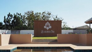 A swimming pool with a sign in the background. - S-Tawan Hotel & Convention (Maha Sarakham)