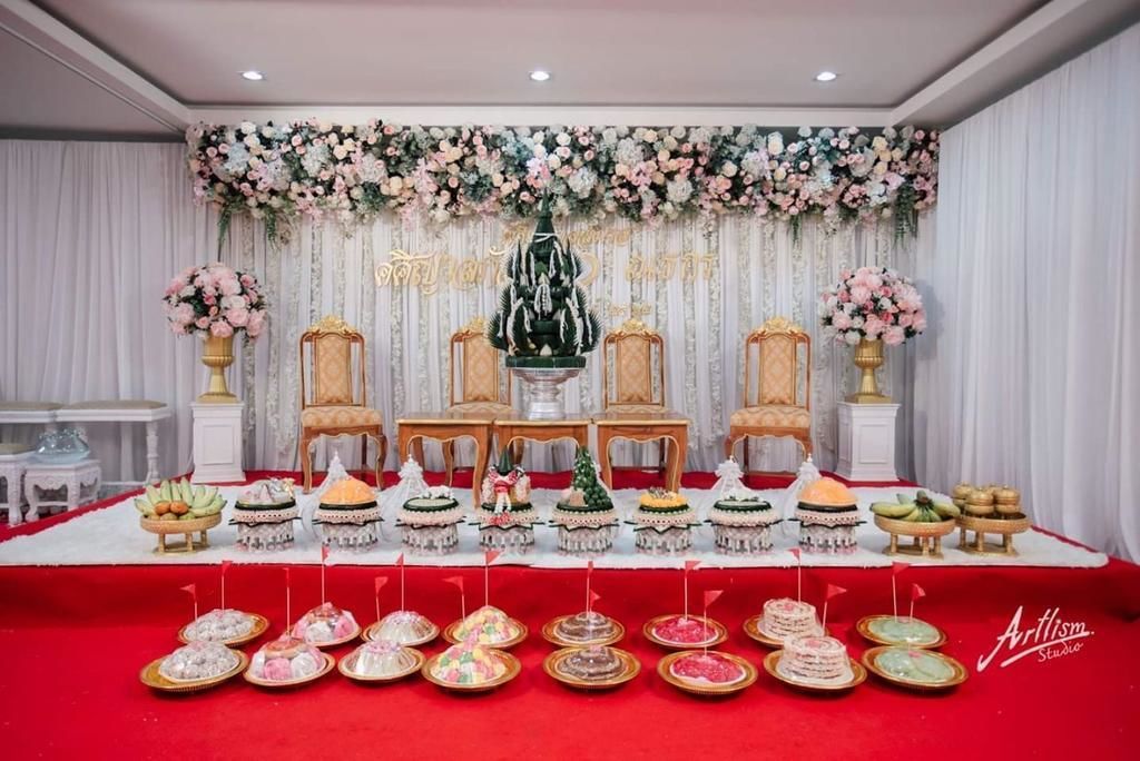 Un escenario decorado para un evento, con arreglos florales, una mesa central con comida y una alfombra roja.