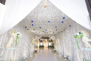 A grand hall with a reflective ceiling, white drapes, and statues on either side. - S-Tawan Hotel & Convention (Maha Sarakham)