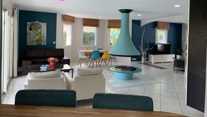 Una sala de estar moderna con comedor, una lámpara colgante azul turquesa grande y un cuadro en la pared.