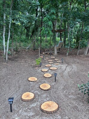 A forested area with a wooden pathway lined with tree stumps and lanterns.