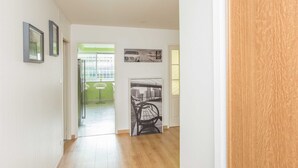 A hallway with a wooden floor, white walls, and a door on the right. There are two framed pictures on the left wall and a black and white photo on the wall in the middle. - Chambre sympa Chambre d'hôtes in the heart of Nancy (Nancy)
