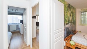 A bedroom with a wooden bed, a nightstand, and a window with a view of a forest. - Chambre sympa Chambre d'hôtes in the heart of Nancy (Nancy)
