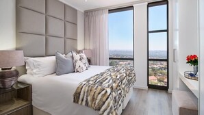 Une chambre moderne avec un grand lit, une vue sur la ville et un balcon.