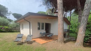 Een huis met een patio, twee lounge fauteuils, een tafel en een overdekte zithoek.