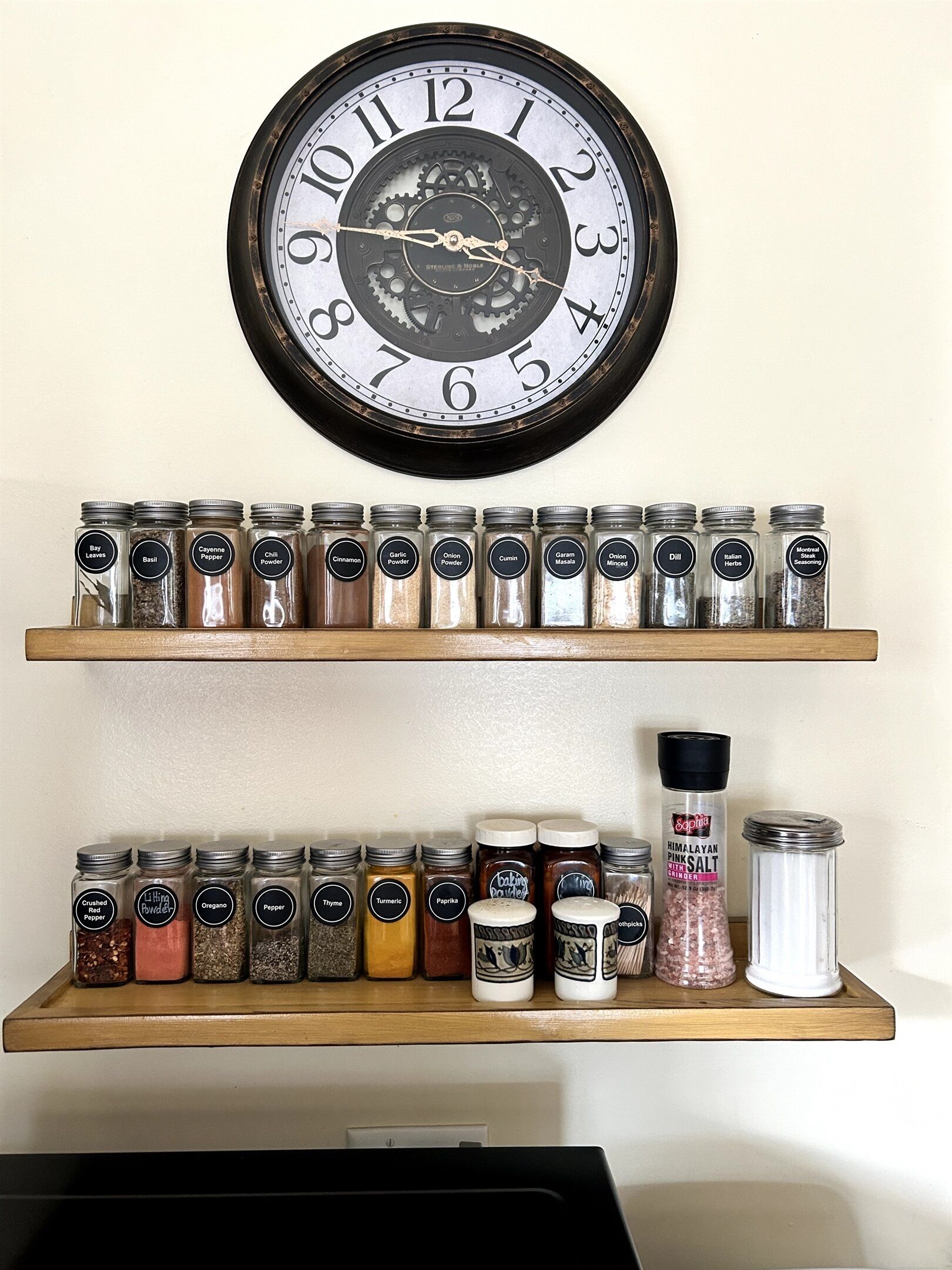 A kitchen with a clock, two spice racks, and various spices.