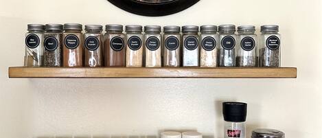 A kitchen with a clock, two spice racks, and various spices.