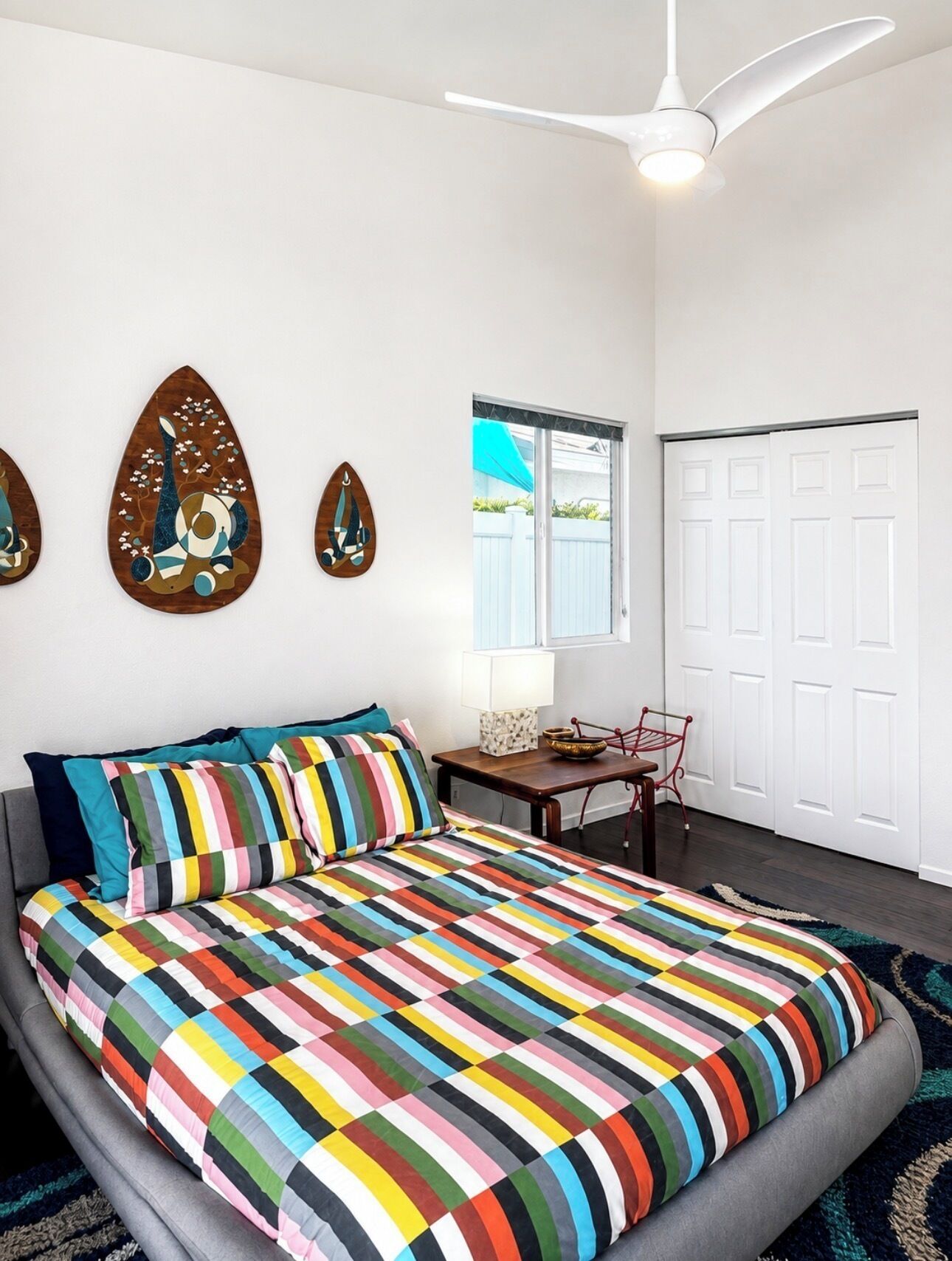 Quarto com cama, escrivaninha, cadeira e ventoinha no teto.