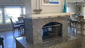 Una sala de estar moderna con chimenea, zona de comedor y un ventanal grande.