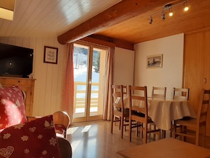 Enjoy a meal for four in this room, which features a dining area with a table and chairs, a television, and a large window with a view.