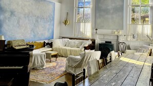 Una habitación con un piano, una cama, una mesa y una chimenea.