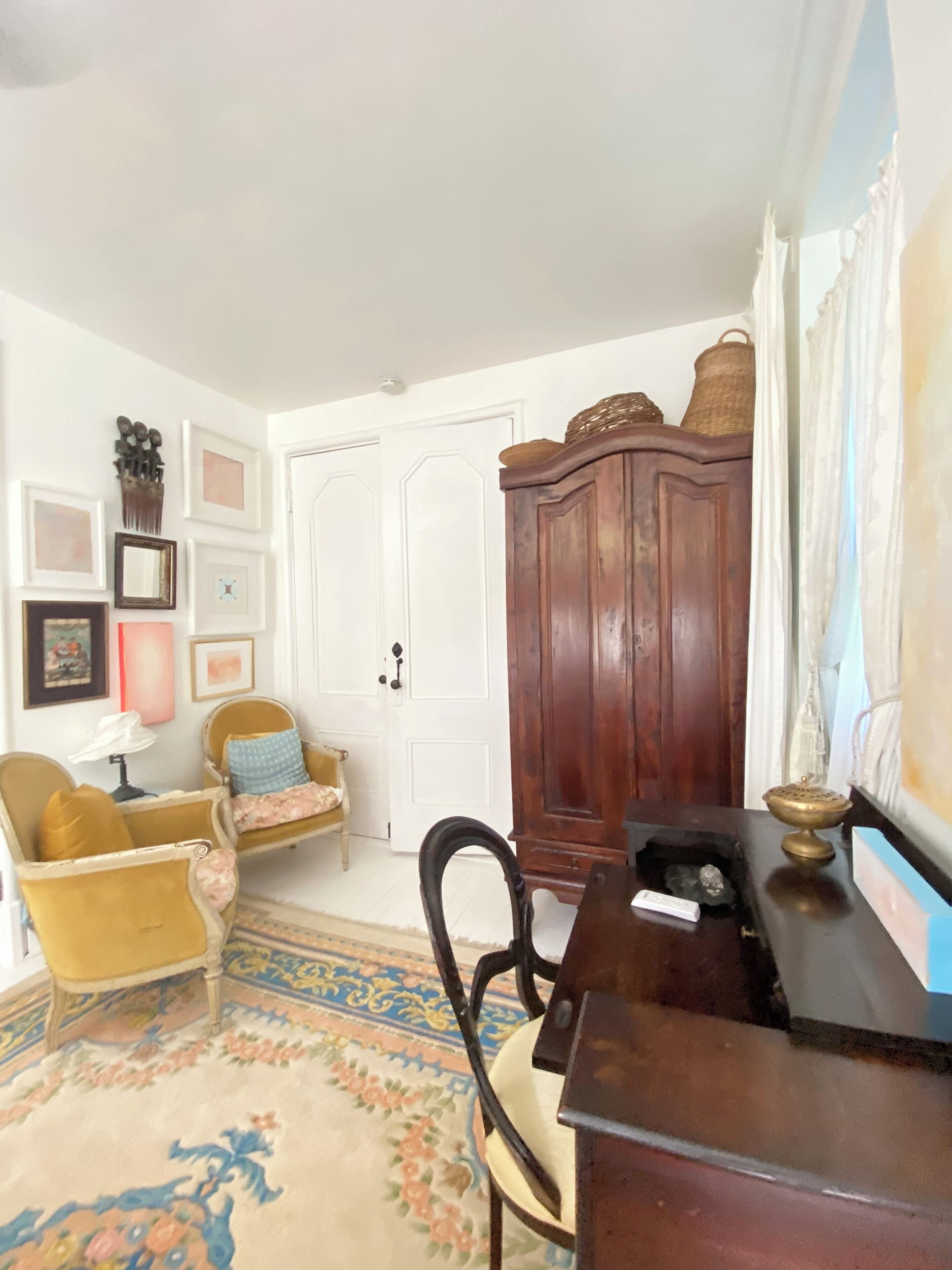 Una habitación con un armario de madera, una silla, un escritorio y una alfombra estampada.
