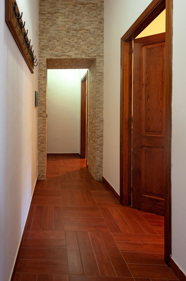Un couloir doté d’un plancher en bois, d’un mur en pierre et d’une porte en bois.