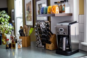 Un plan de travail de cuisine avec une machine à café, un bloc à couteaux et divers condiments rangés sur une étagère.