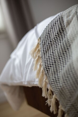 Primer plano de una cama con un almohadón blanco y una colcha estampada.