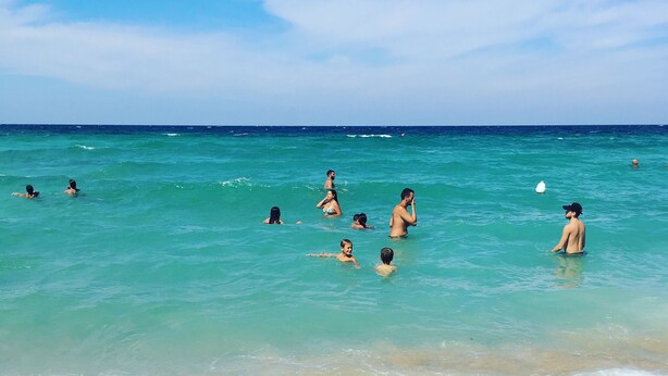 Une scène de plage avec une eau turquoise et limpide et de douces vagues.