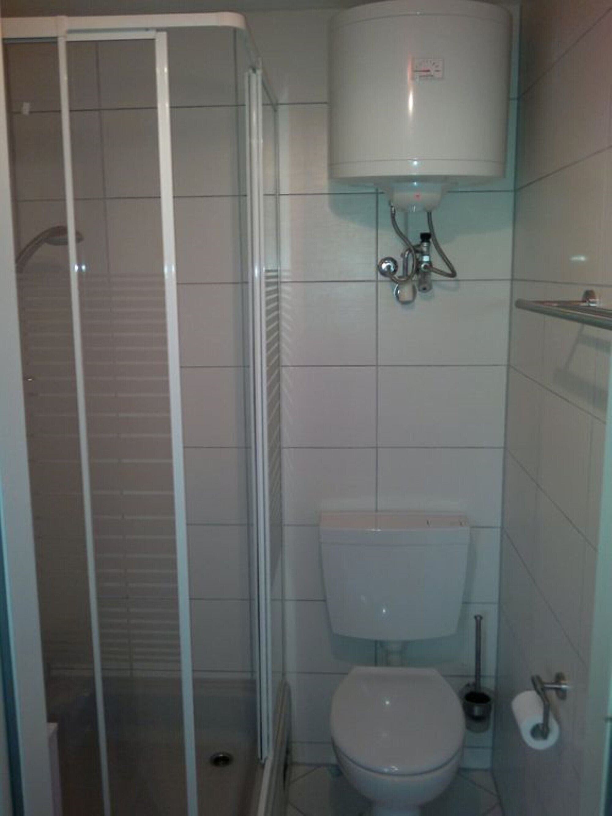 A bathroom with a glass-enclosed shower, a white toilet, and a visible water heater.