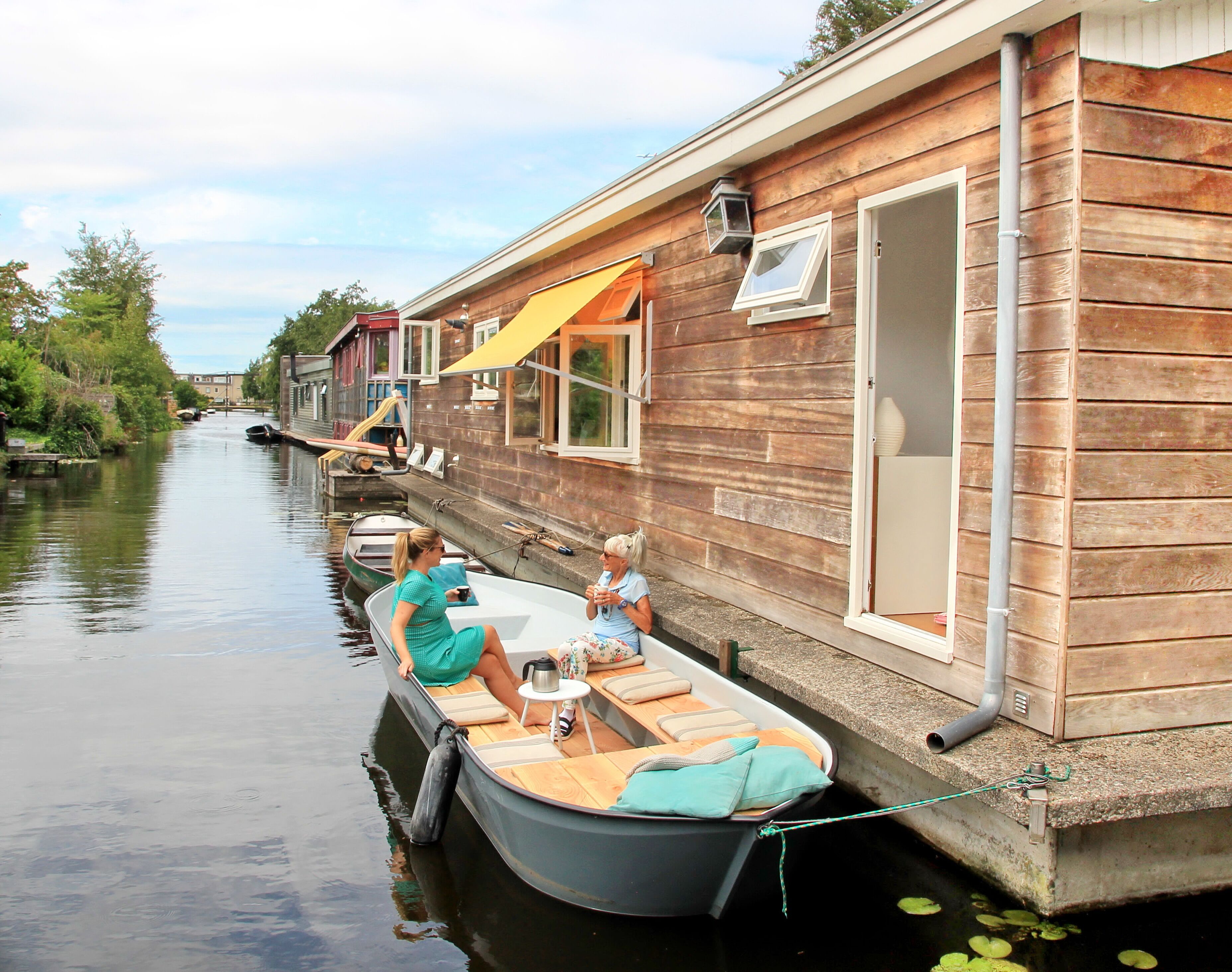 Ein Hausboot mit kleinem Deck, einem Tisch und einem Stuhl.