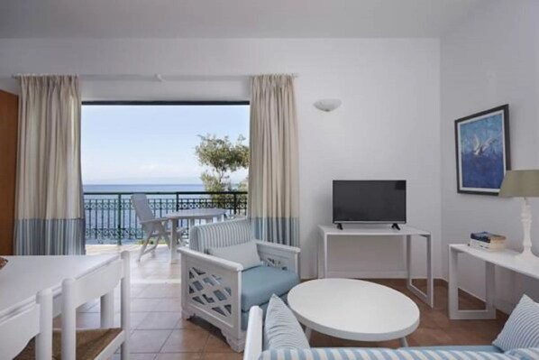 A hotel room with a balcony, a TV, a round table, and a sofa. - 2 Bedroom Residence Sea View (Paxoi)