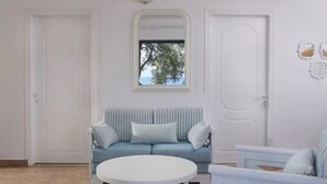 A room with a light blue sofa, a white round table, and a window with a view of trees. - 2 Bedroom Residence Sea View (Paxoi)
