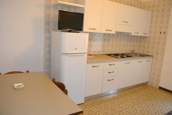 Een koelkast, kookgerei, borden en bestek