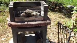 A portable outdoor grill with a metal grate and a firewood log inside. - An atmisfera suspended in time - Camera Brezza (Tresana)