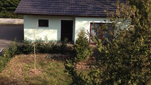 A small, single-story house with a dark roof, light walls, and a small front porch.