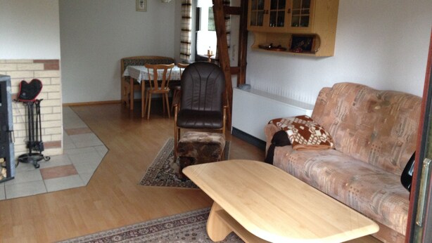 A living room with a wooden table, a sofa, a dining table with chairs, and a fireplace.