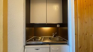 A compact kitchenette with a built-in stove, sink, and storage cabinets.