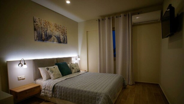 A bedroom with a bed, nightstands, a wall-mounted TV, and a painting. - Sandika apartment 8. The right place to be!!! (Koutouloufari)