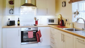 A kitchen with white cabinets, a microwave, a stove, and a sink.