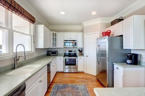 A kitchen with white cabinets, a stainless steel refrigerator, a microwave, an oven, and a dishwasher.