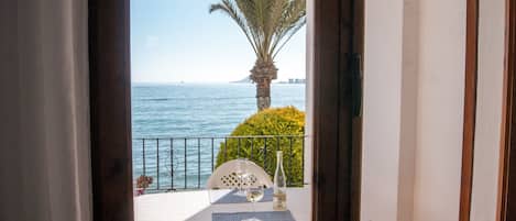 Ein Balkon mit Tisch für zwei Personen, einer Weinflasche und einem Glas.