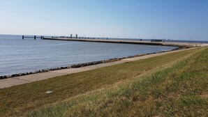 A coastal walkway with a grassy path and a pier extending into the water. - Apartment "Blied" f. Max. 2 pers + toddler, san. Gulfhof, gr. garden (Manslagt)