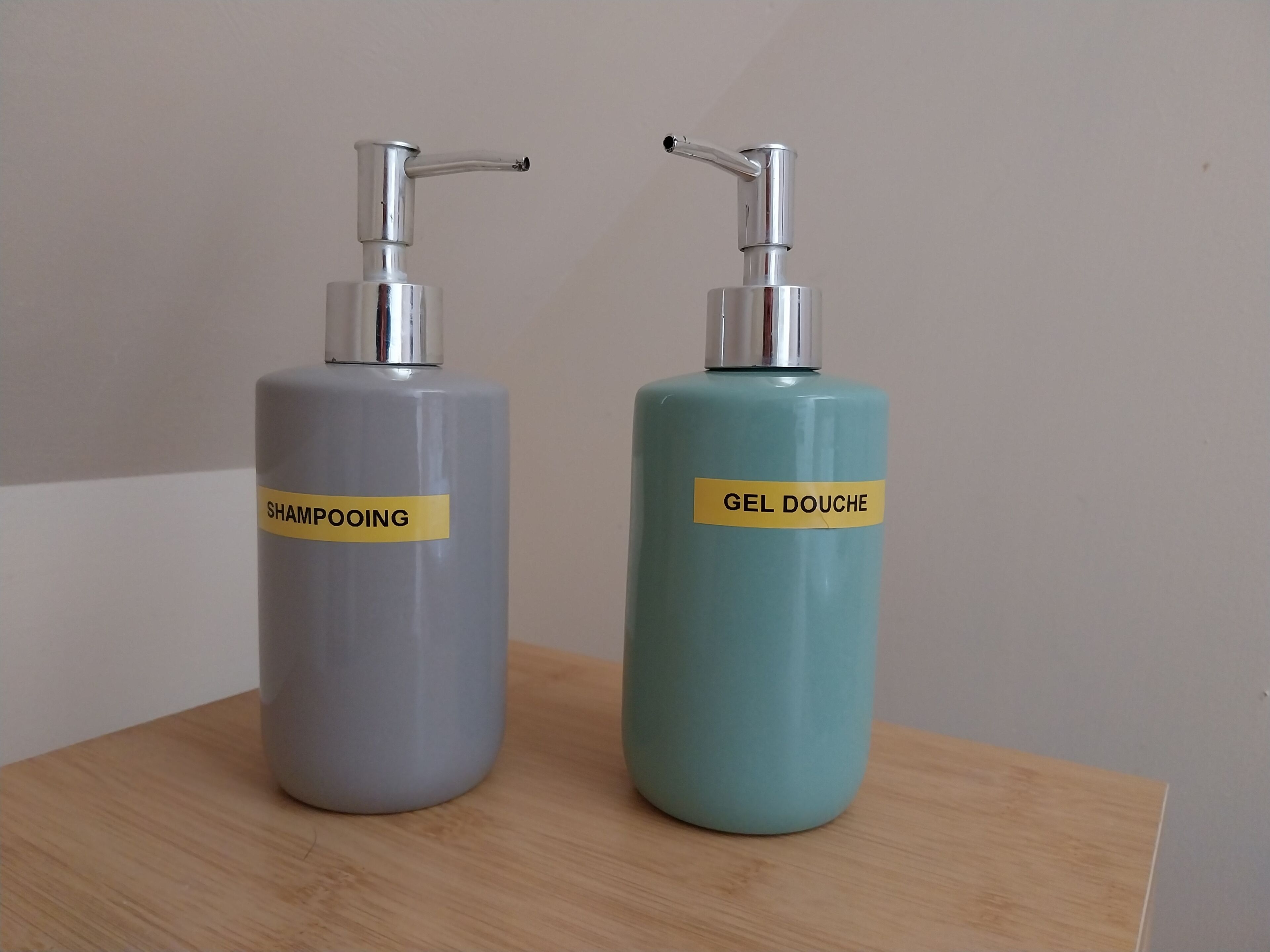 Two cylindrical bottles with pump dispensers on a wooden surface.