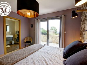 Een slaapkamer met een bed, een stoel, een grote spiegel en uitzicht.