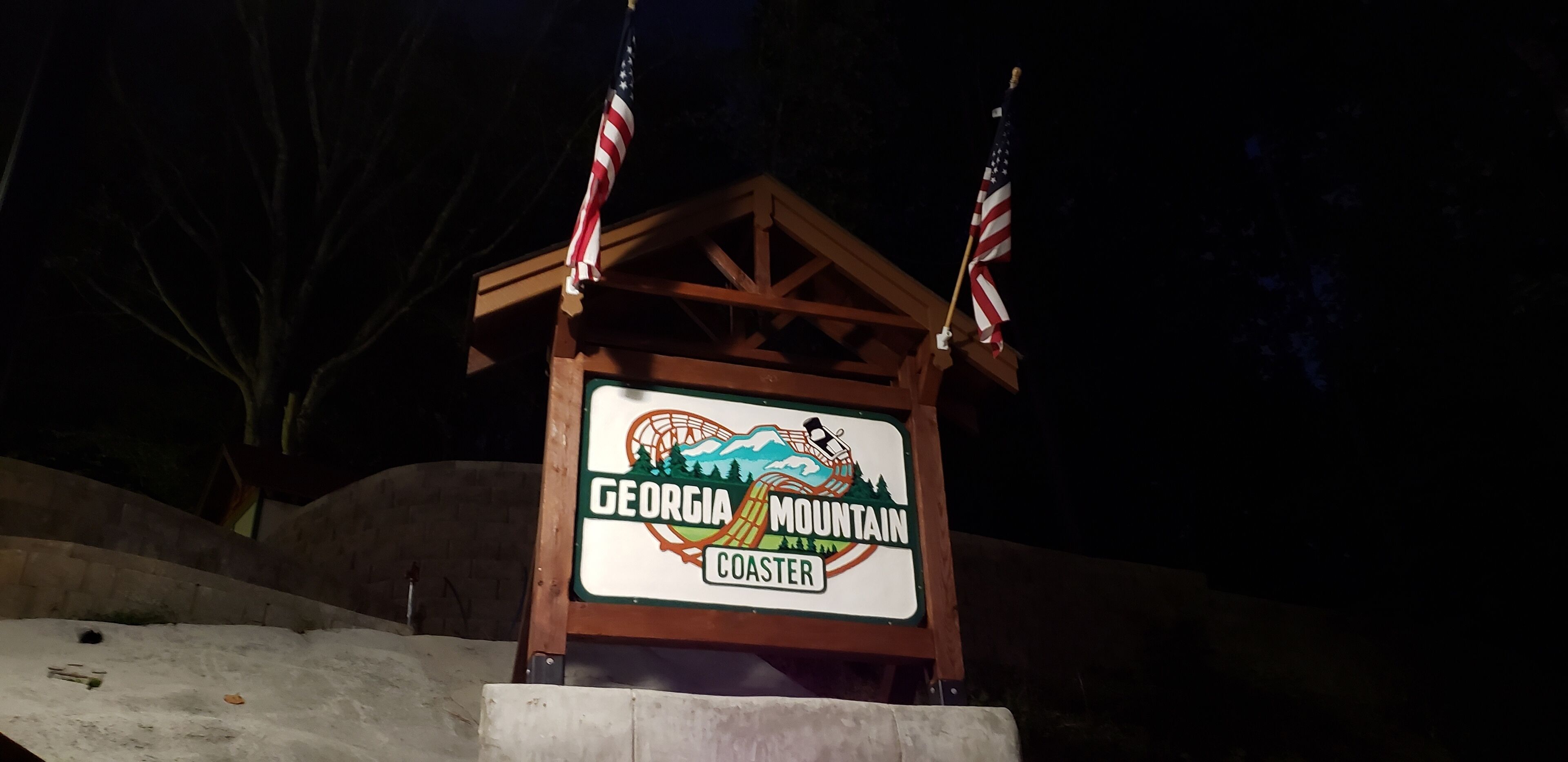 A wooden sign with the text "Georgia Mountain Coast" and two American flags.