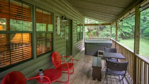 A covered porch with wooden flooring, a barbecue grill, and outdoor seating.