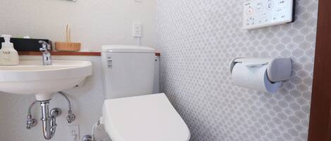 A bathroom with a sink, toilet, and a toilet paper holder.