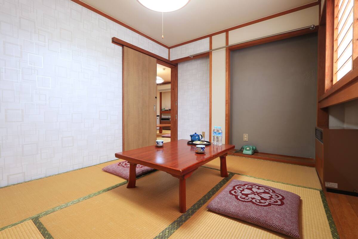 A traditional Japanese room with tatami flooring, a wooden table, and sliding doors.