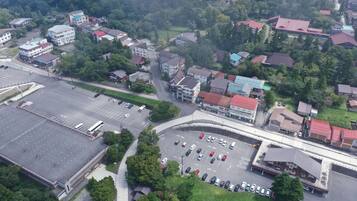 An aerial view of a parking lot with multiple cars, surrounded by buildings with red roofs and a large building with a flat roof.