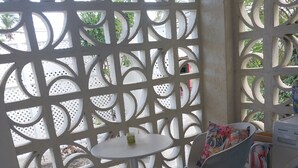 A room with a white tiled floor, a round table with two chairs, and a white partition with a geometric pattern. - Beachside Apartment #2 - steps from the beach! (Bridgetown)